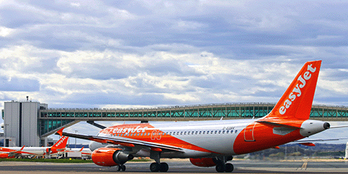 a photo of an easyJet a320 taxiing underneath the pier 6 bridge on a sunny day
