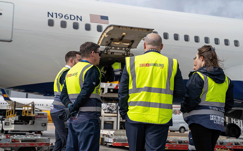 A group of ground handling agents in a huddle meeting next to a plane