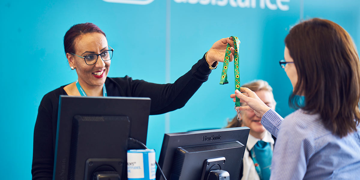 Image showing Special Assistance host giving a hidden disabilities lanyard to a passenger