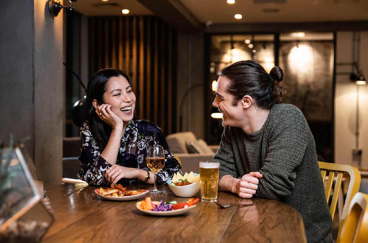 Couple laugh over drinks and food in My Lounge London Gatwick