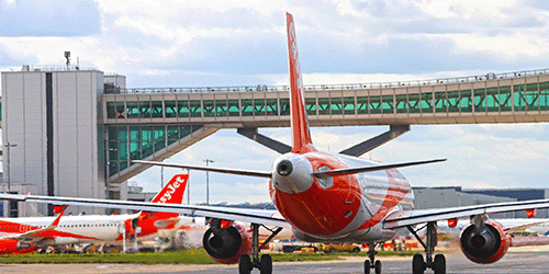 a photo of an easyJet a320 taxiing underneath the pier 6 bridge on a sunny day