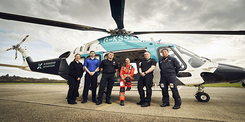 A photo of Gatwick staff and AAKSS personnel in front of an air ambulance helicopter