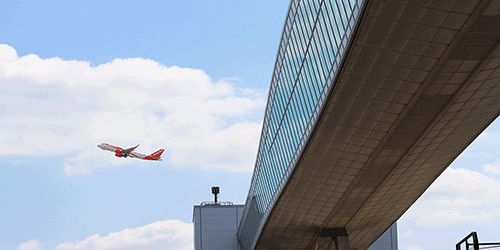 a closeup photo of the pier 6 bridge, a sunny blue sky and an easyJet plane taking off in the background