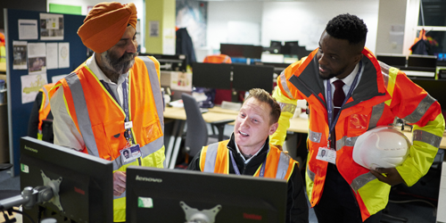 A photo of three construction team member chatting over a computer