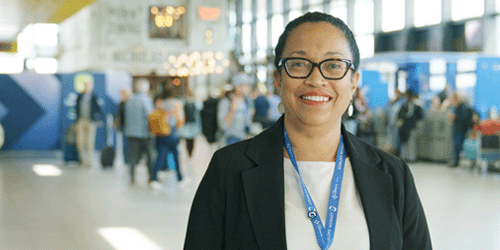 headshot photograph of Lisa Chang Fong standing in the North Terminal departures hall, smiling