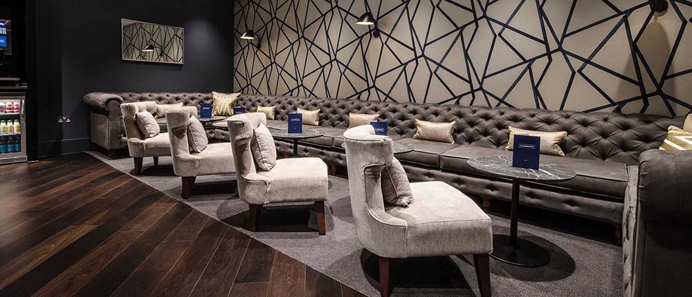 Plush chairs positioned around luxurious granite table tops in Gatwick Airport's Clubrooms Lounge