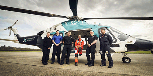 a photo of Gatwick colleagues and air ambulance staff lined up in front of an air ambulance helicopter at Redhill aerodrome
