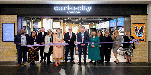 ribbon cutting opening of the curiocity shop at London Gatwick, with staff of the shop and London Gatwick lined up