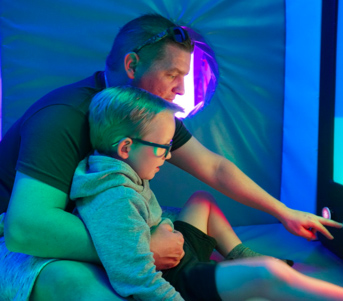 A man shows his son one of the interactive features within the Gatwick Sensory Room