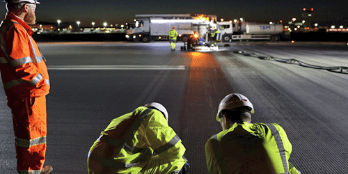 photo of two engineers inspecting the runway during a resurfacing at night