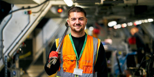 Portrait photograph of a Gatwick engineer with a large wrench in a room full of machinery