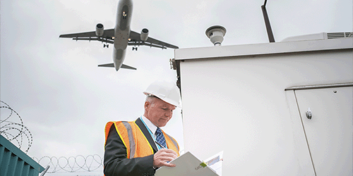 A photo of a man in a high vis standing underneath the LGW flight path