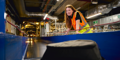 a young female Gatwick engineer with a wrench performing maintenance on some machinery