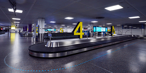 an artistic photo of the numbered baggage claim carousels and advertising screens at London Gatwick